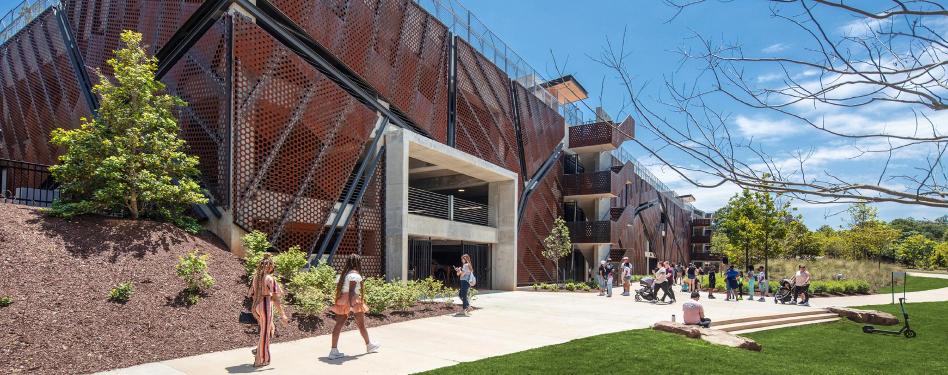 Students walk past a building on a college campus.