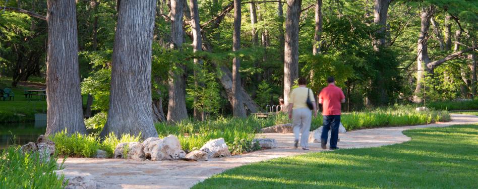 Two people stroll along a wooded pathway.