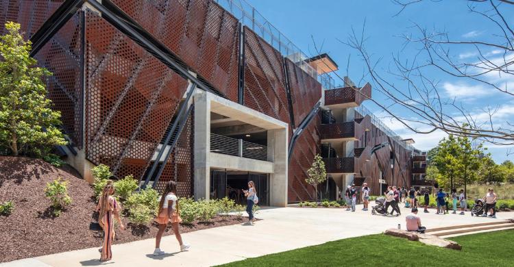 Students walk past a building on a college campus.